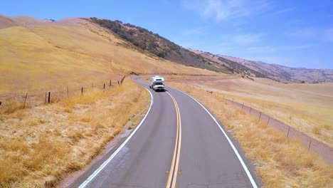 An-aerial-over-a-camper-van-traveling-along-a-road-in-Central-California-