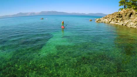 An-aerial-shot-of-a-woman-and-her-dog-paddle-boarding-on-Lake-Tahoe-1