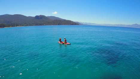 An-aerial-shot-of-a-woman-and-man-sitting-on-a-paddle-board-on-Lake-Tahoe