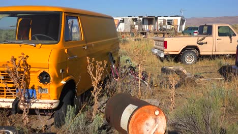 An-abandoned-mobile-home-in-the-desert-is-surrounded-by-old-trucks-and-cars-and-trash-2