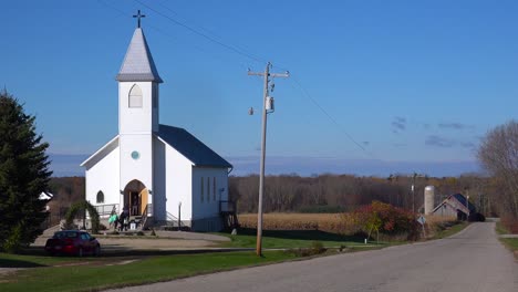 Churchgoers-arrive-at-a-pretty-white-church-in-the-countryside