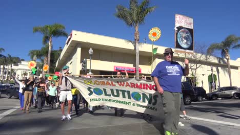 Global-warming-advocates-march-holding-signs-through-an-urban-area