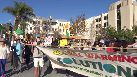 Global-warming-advocates-march-holding-signs-through-an-urban-area-2