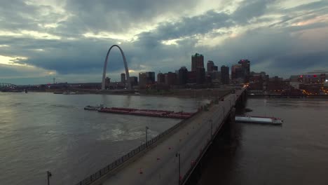 Schöne-Antenne-über-Einem-Mississippi-Flusslastkahn-Und-Einer-Brücke-Mit-Dem-Skyline-Hintergrund-Von-St.-Louis-Missouri