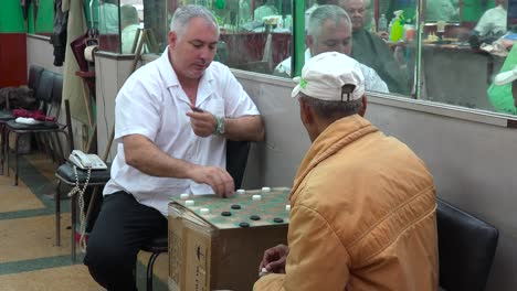 Zwei-Männer-Spielen-Dame-In-Einem-Friseurladen-In-Havanna,-Kuba