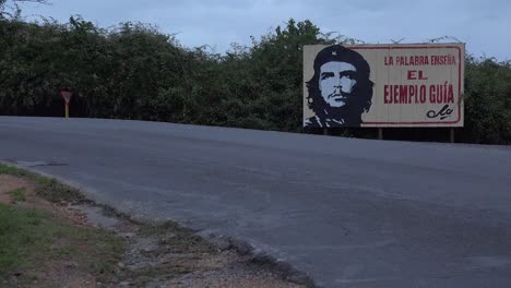 Communist-propaganda-billboards-line-a-road-in-Cuba-with-classic-old-car-passing