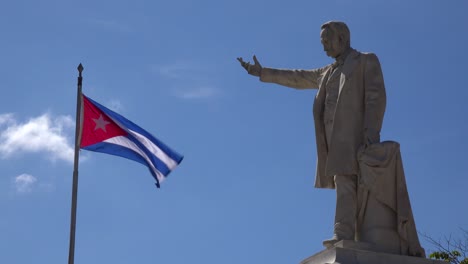 The-flag-of-Cuba-flies-in-the-sky-with-a-statue-of-Jose-Marti-in-the-foreground