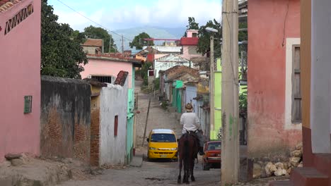 A-beautiful-shot-of-the-buildings-and-cobblestone-streets-of-Trinidad-Cuba-with-cowboy-riding-past