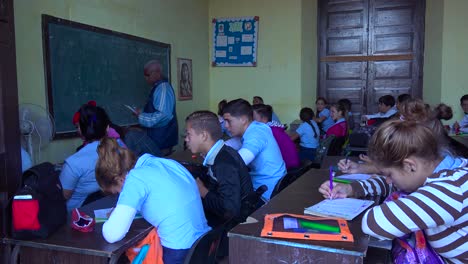 Students-study-in-a-classroom-in-Cuba-as-a-teacher-looks-on-1