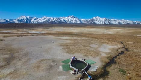 Eine-Antenne-über-Einem-Mann-In-Einem-Natürlichen-Heißen-Pool-In-Den-Sierra-Nevada-Bergen-In-Der-Nähe-Von-Mammut-Kalifornien