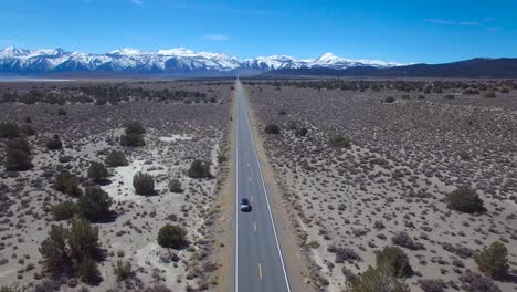 Aerial-above-a-4WD-traveling-on-a-paved-road-in-the-Mojave-Desert-with-the-Sierra-Nevada-mountains-distant-1