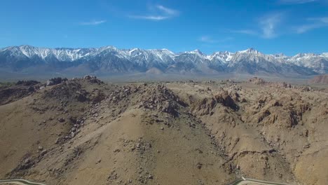 A-rising-aerial-over-the-Alabama-Hills-of-California-reveals-the-towering-and-snow-covered-Sierra-Nevada-mountains-1