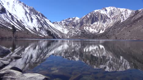 An-alpine-mountain-lake-reflects-sierra-nevada-snow-in-winter-