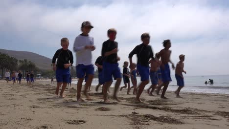Kinder-Laufen-An-Einem-Strand-Entlang-In-Einem-Tagescamp-Am-Strand-In-Santa-Barbara,-Kalifornien