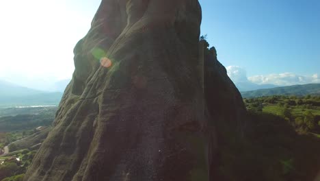 Rising-aerial-as-climbers-ascend-a-sheer-pinnacle-spire-in-Meteora-Greece