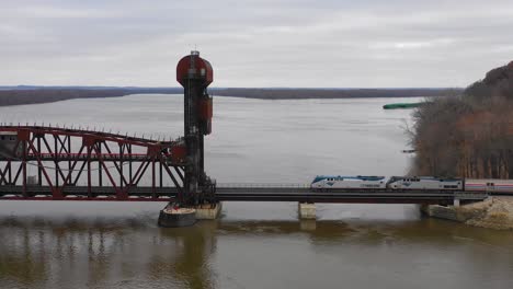 Drone-aerial-footage-of-an-Amtrak-passenger-train-crossing-the-Mississippi-River-on-a-drawbridge-at-Burlington-Iowa