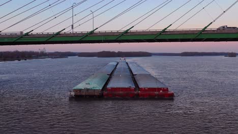 Drone-aerial-footage-of-a-huge-barge-traveling-under-a-highway-bridge-on-the-Mississippi-River-near-Burlington-Iowa