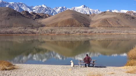 A-man-and-his-dog-enjoy-a-beautiful-day-at-a-lake-at-the-base-of-Mt-Whitney-and-the-Sierra-Nevada-mountains-near-Lone-Pine-California