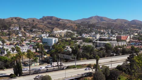 A-drone-aerial-of-Southern-California-beach-town-of-Ventura-California-with-freeway-foreground-and-mountains-background-1