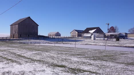 Establishing-shot-of-a-classic-beautiful-small-town-farmhouse-farm-and-barns-in-rural-midwest-America-in-winter-snow