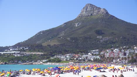 Establishing-shot-of-a-beautiful-busy-holiday-beach-scene-at-Camps-Bay-Cape-Town-South-Africa-with-Lions-Head-peak-background-2
