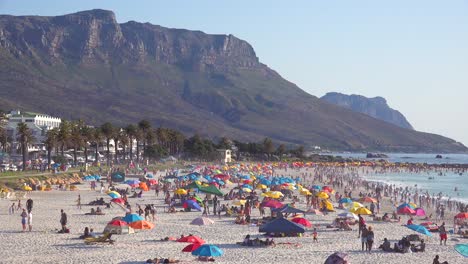 Eine-überfüllte-Und-Geschäftige-Urlaubsstrandszene-In-Camps-Bay-Kapstadt-Südafrika-Mit-Zwölf-Apostelbergen-Im-Hintergrund-3