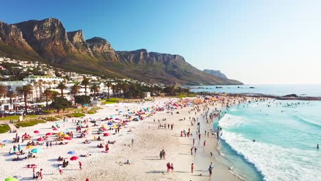 Spectacular-aerial-over-a-crowded-and-busy-holiday-beach-at-Camps-Bay-Cape-Town-South-Africa-with-Twelve-Apostles-mountains-background-3