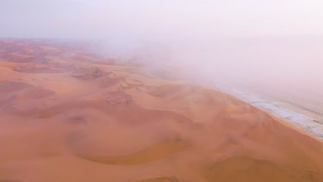 Good-high-aerial-shot-through-clouds-and-fog-over-the-vast-sand-dunes-of-the-Namib-Desert-along-the-Skeleton-Coast-of-Namibia-1