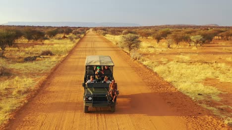 Aerial-of-a-safari-jeep-traveling-on-the-plains-of-Africa-at-Erindi-Game-Preserve-Namibia-with-native-San-tribal-spotter-guide-sitting-on-front-spotting-wildlife-2