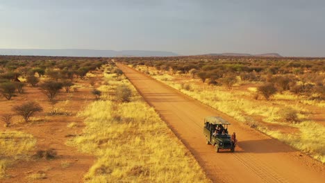 Aerial-of-a-safari-jeep-traveling-on-the-plains-of-Africa-at-Erindi-Game-Preserve-Namibia-with-native-San-tribal-spotter-guide-sitting-on-front-spotting-wildlife-3