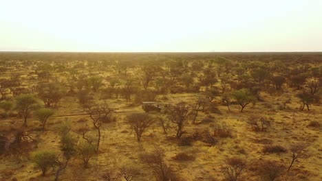 Excellent-aerial-of-a-safari-jeep-traveling-on-the-plains-of-Africa-at-Erindi-Game-Preserve-Namibia-with-native-San-tribal-spotter-guide-sitting-on-front-spotting-wildlife-1