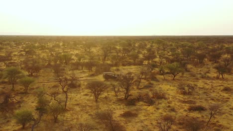 Aerial-of-a-safari-jeep-traveling-on-the-plains-of-Africa-at-Erindi-Game-Preserve-Namibia-with-native-San-tribal-spotter-guide-sitting-on-front-spotting-wildlife-7