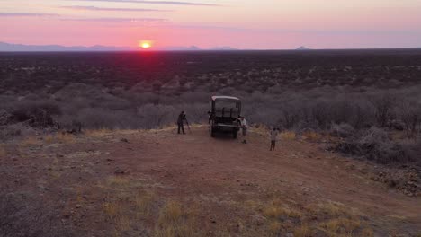 Antena-De-Turistas-Disfrutando-De-Una-Atardecer-En-Un-Jeep-De-Safari-En-La-Vasta-Y-Hermosa-Reserva-De-Caza-Erindi-Namibia