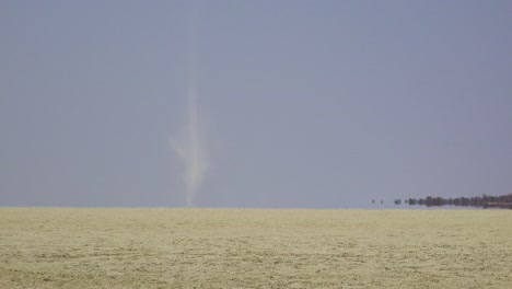 A-dust-devil-blows-across-the-dry-and-desolate-Etosha-Pan-in-Namibia