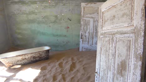 Sand-and-a-bath-tub-fills-an-abandoned-building-in-the-gem-mining-ghost-town-of-Kolmanskop-Namibia-1