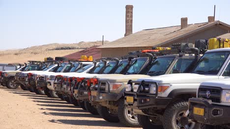 Dozens-of-safari-jeep-vehicles-parked-in-a-row-at-a-popular-desert-attraction-in-Namibia