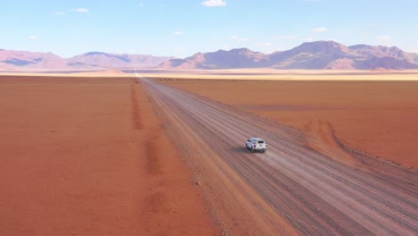 High-aerial-over-a-Toyota-safari-vehicle-heading-across-the-flat-barren-Namib-Desert-in-Namibia-2