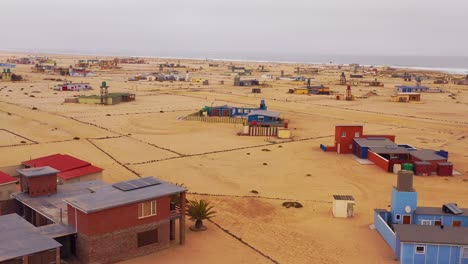 Aerial-over-a-strange-lonely-barren-post-apocalyptic-beach-side-settlement-of-summer-homes-at-Hengtiesbaai-Namibia