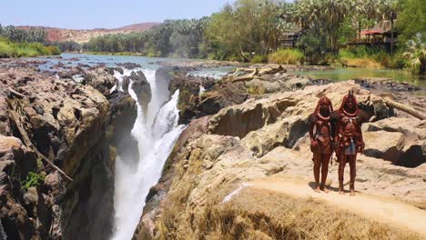 Aerial-reveals-two-Himba-tribal-women-girls-in-front-of-Epupa-waterfalls-on-the-Angola-Namibia-border-Africa-4