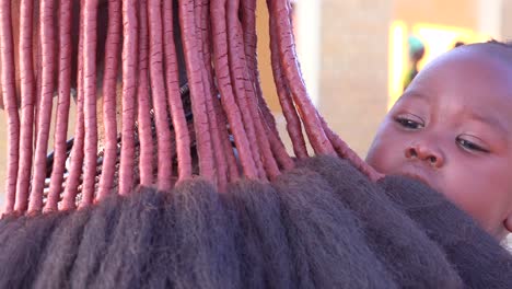 Eine-Himba-Stammesfrau-Zeigt-Ihre-Geflochtene,-Schlammverkrustete-Dreadlock-Frisur-Auf-Einem-Markt-In-Opuwo,-Namibia-2