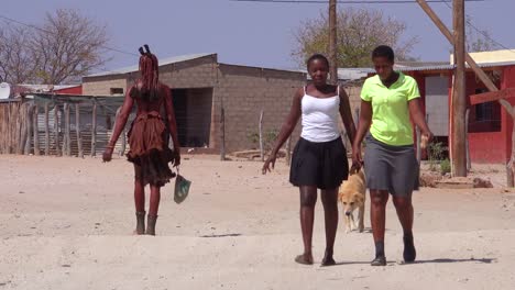 Modern-and-traditional-Himba-tribal-women-walk-on-a-street-in-a-small-village-in-Damaraland-Namibia