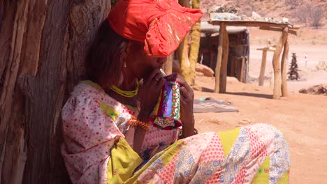 Eine-Afrikanische-Herero-Stammesfrau-In-Hellen-Modekostümen-Näht-Von-Hand-Auf-Einem-Marktplatz-In-Namibia-Afrika