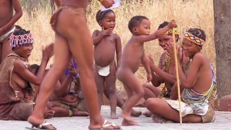 Afrikanische-San-Buschmänner-Frauen-Kinder-Und-Stammes-Eingeborene-Sitzen-In-Einem-Kreis-Singen-Und-Klatschen-In-Einem-Kleinen-Dorf-In-Namibia-1