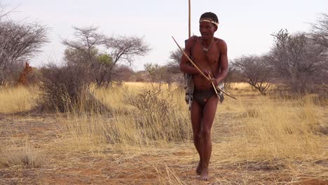 Ein-San-Tribal-Buschmann-Jäger-In-Namibia-Afrika-Geht-Leise,-Schnuppert-Die-Luft-Und-Probiert-Den-Boden-Für-Die-Windrichtung-Auf-Der-Jagd-Nach-Beute-1
