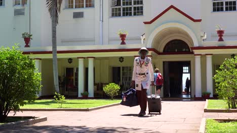 A-porter-or-bellman-in-colonial-outfit-brings-tourist-luggage-from-the-posh-and-elegant-Victoria-Falls-Hotel-in-Zimbawbwe
