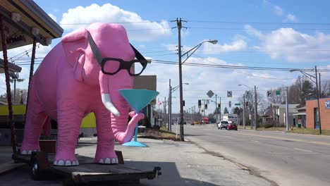 A-giant-pink-elephant-sits-beside-the-road-with-a-martini-in-its-trunk-in-a-small-town-in-rural-Fortville-Indiana