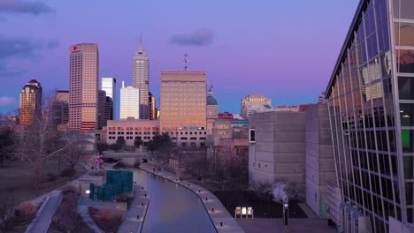 Nice-drone-aerial-of-downtown-Indianapolis-Indiana-at-dusk-or-night-with-riverwalk-foreground