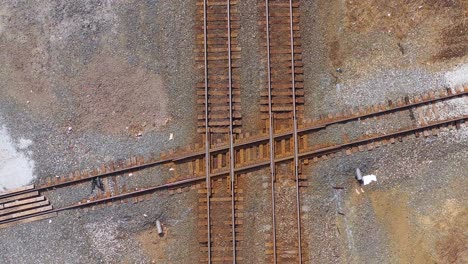 Aerial-looking-straight-down-over-a-railroad-track-intersection-with-a-freight-train-passing-underneath