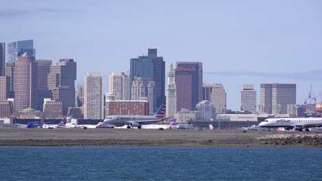 Flugzeuge-Taxi-Auf-Einer-Start--Und-Landebahn-Am-Internationalen-Flughafen-Logan-Boston-Mit-Skyline-Hintergrund-Der-Stadt