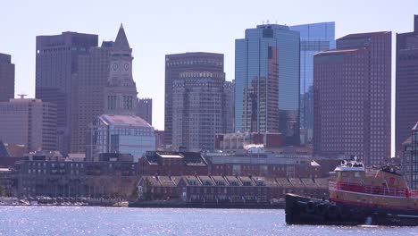 A-tugboat-moves-in-front-of-the-downtown-city-skyline-and-financial-district-of-Boston